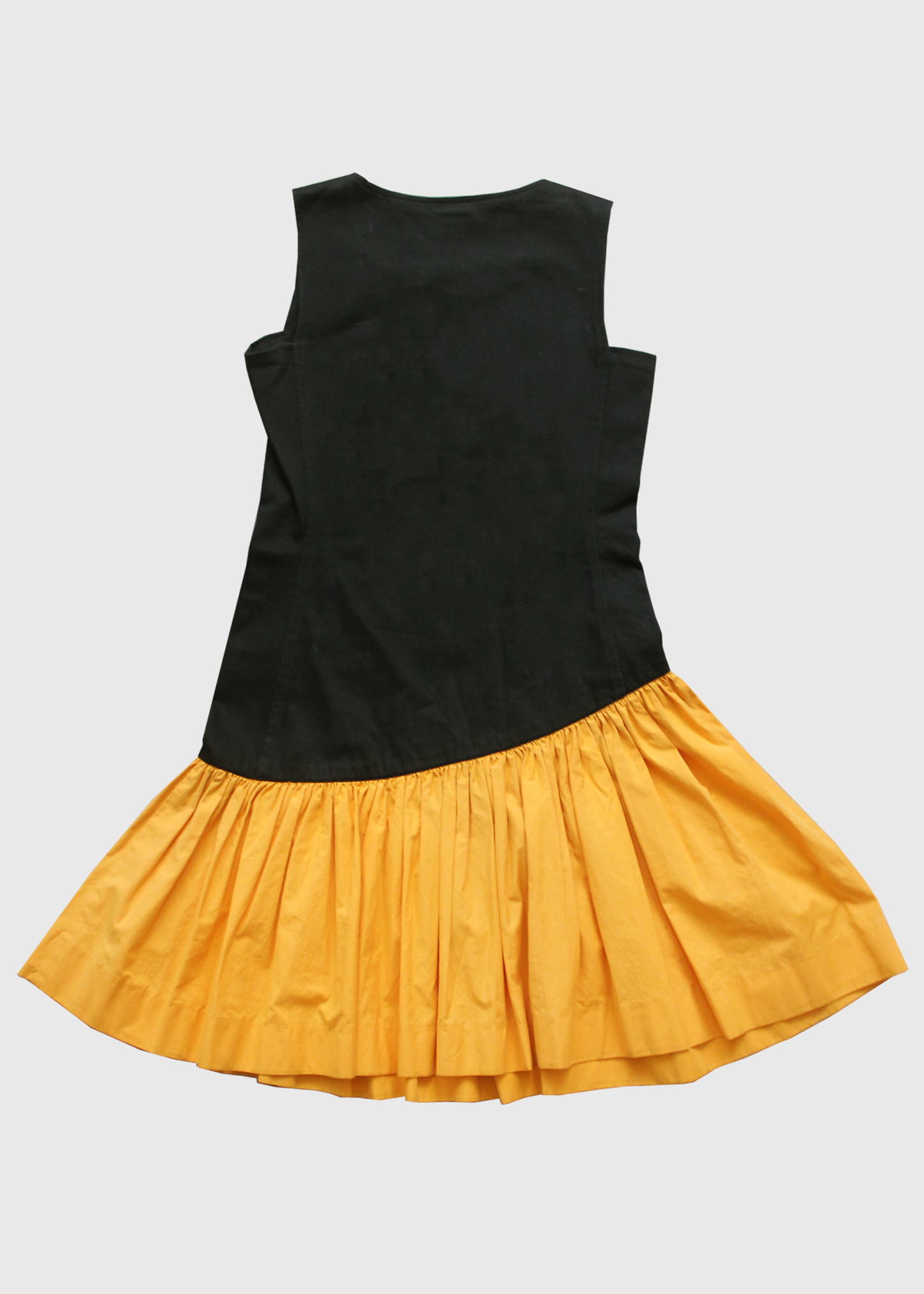 1980s incredible black YSL knee-length dress featuring a full, color-blocked, slanted marigold yellow cotton ruffled hem starting at the hip and ending above the knee. Buttons up on one side.
