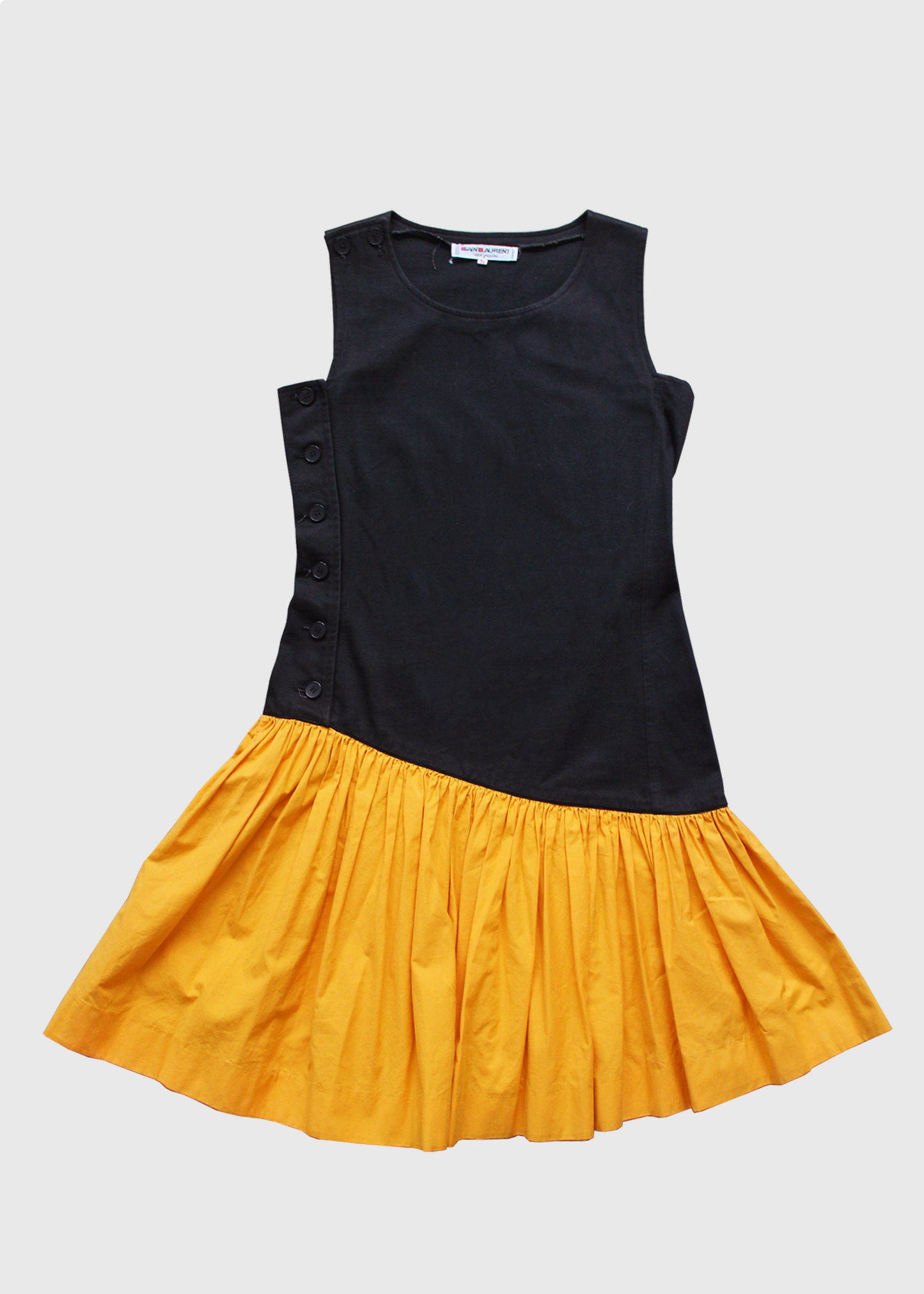 1980s incredible black YSL knee-length dress featuring a full, color-blocked, slanted marigold yellow cotton ruffled hem starting at the hip and ending above the knee. Buttons up on one side.