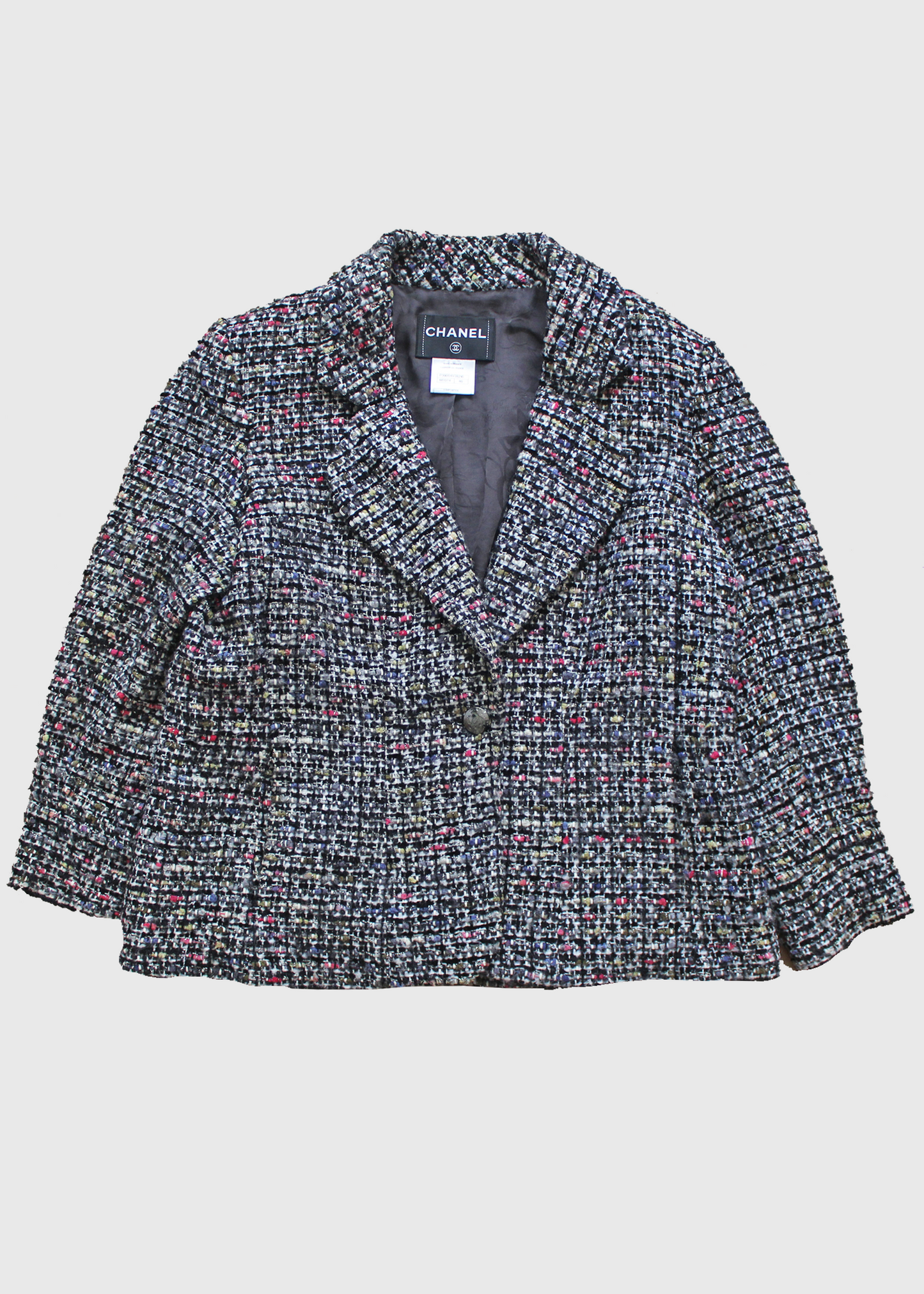 Black, white, and multicolor silk-blended tweed jacket with two slit pockets on the front, a notch collar and 'CC' buttoned cuffs. CC button closure at front. Lined in black Camellia printed silk and has a silver signature chain around the inside of the hemline.