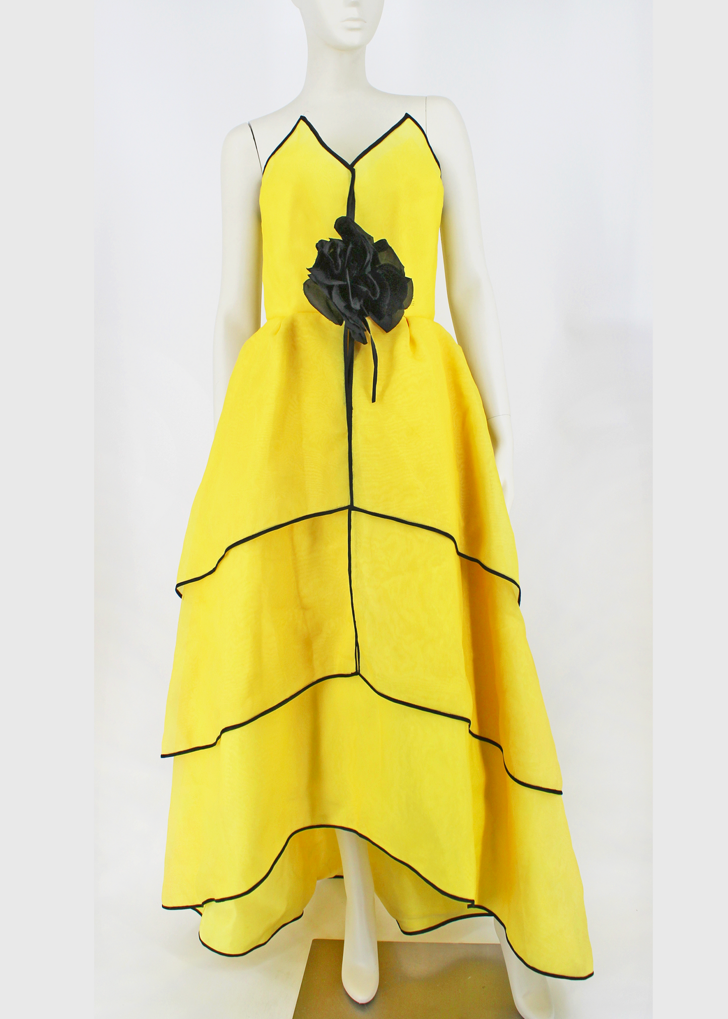 An absolutely breathtaking Victor Costa gown from the 1960s featuring layers of bright yellow organza, an architectural bodice, black piping along the hem of every layer of the dresses skirt and neckline, and an oversized black flower embellishment at front. Slightly higher in the front than in the back.