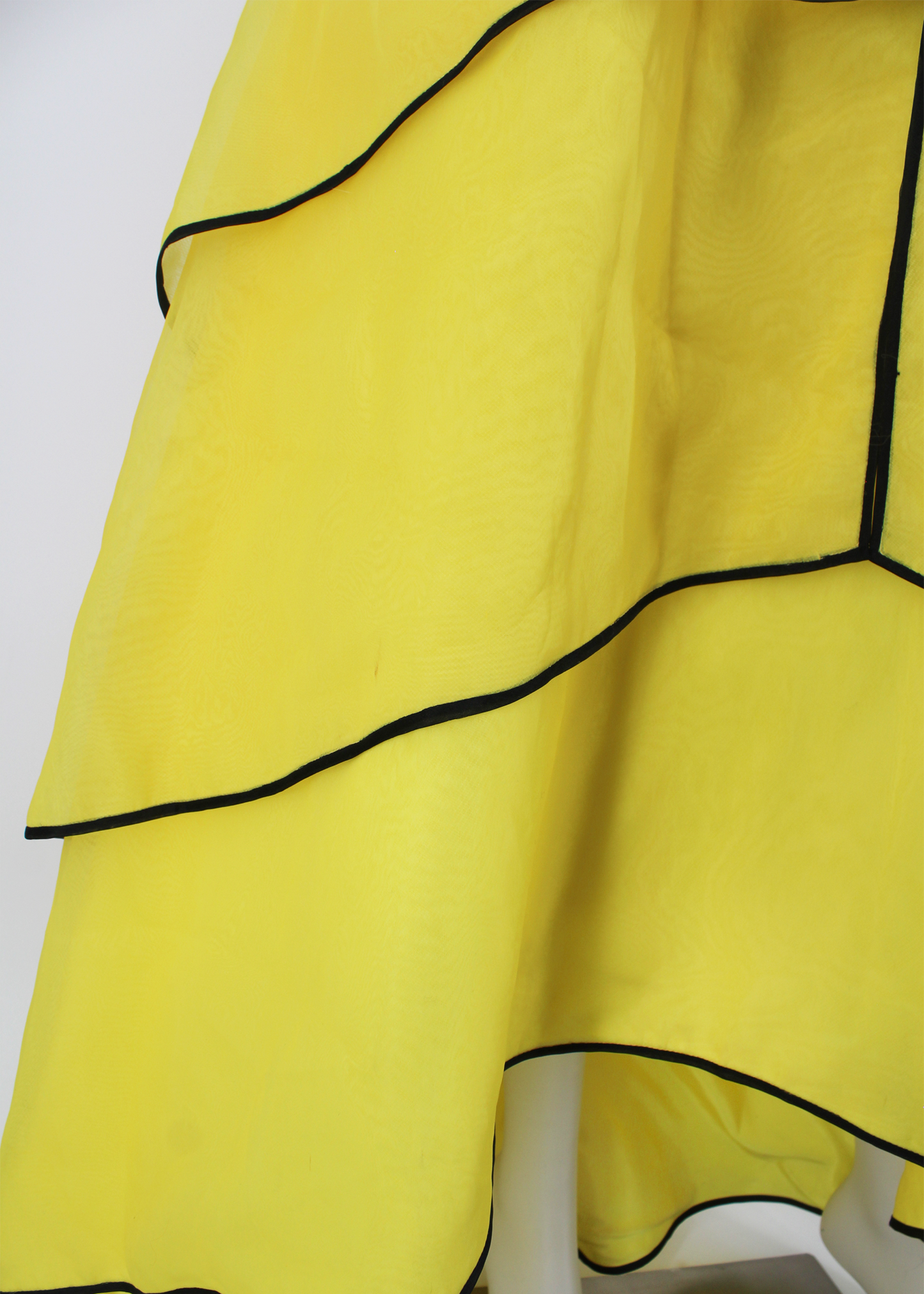 An absolutely breathtaking Victor Costa gown from the 1960s featuring layers of bright yellow organza, an architectural bodice, black piping along the hem of every layer of the dresses skirt and neckline, and an oversized black flower embellishment at front. Slightly higher in the front than in the back.