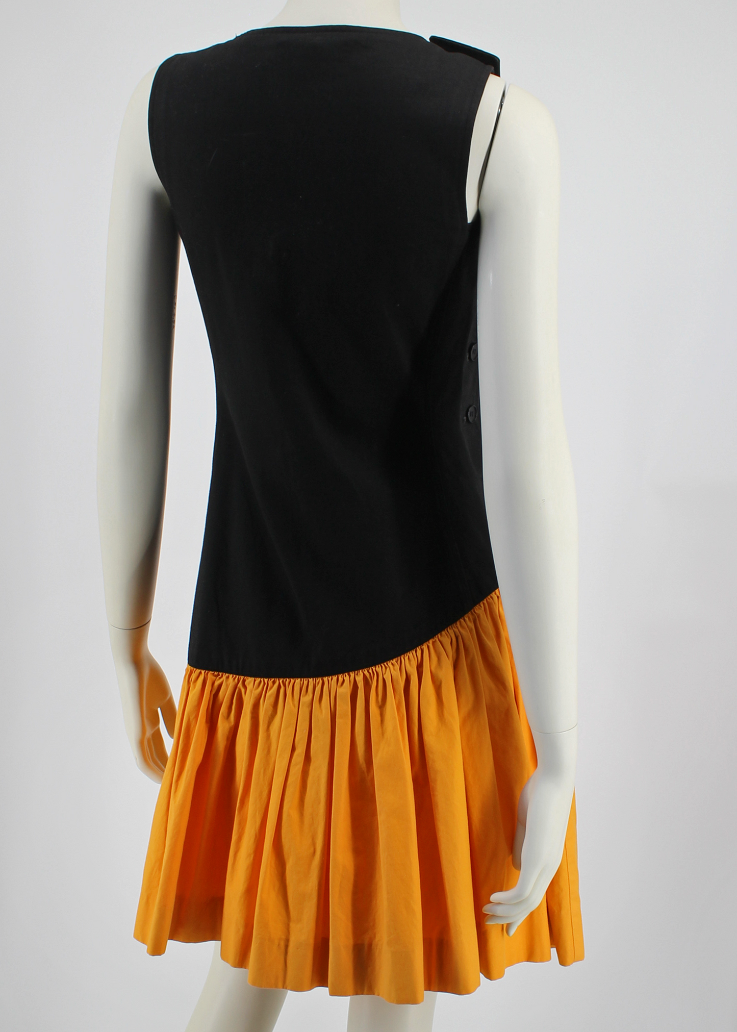 1980s incredible black YSL knee-length dress featuring a full, color-blocked, slanted marigold yellow cotton ruffled hem starting at the hip and ending above the knee. Buttons up on one side.