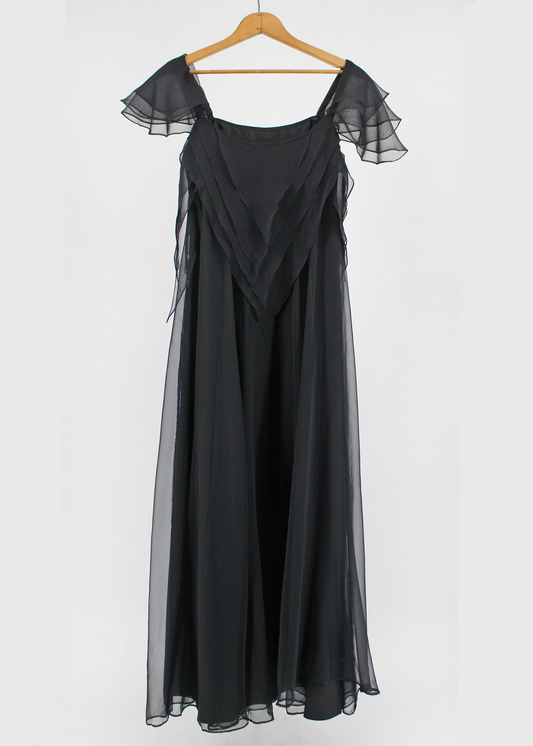 This is a Floor-length, black handkerchief tiered organza dress by London-based designer Jean Varon. The dress features Many, many layers of lightweight black organza are layered and draped to create a waterfall effect that flows as you walk.