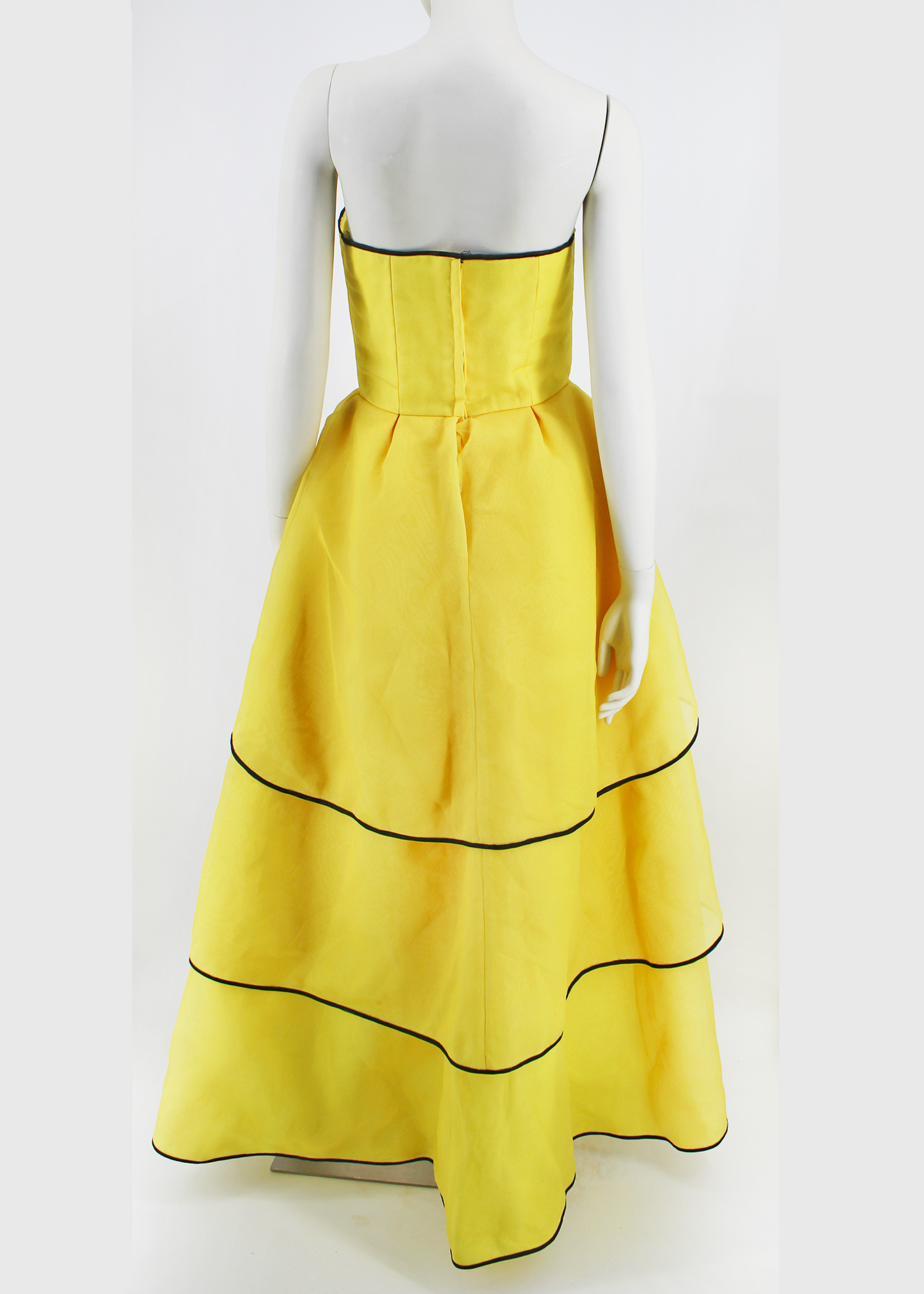 An absolutely breathtaking Victor Costa gown from the 1960s featuring layers of bright yellow organza, an architectural bodice, black piping along the hem of every layer of the dresses skirt and neckline, and an oversized black flower embellishment at front. Slightly higher in the front than in the back.
